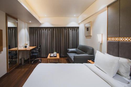 Safal Retreat في بوبال: غرفة في الفندق بسرير وكرسي ومكتب