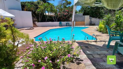 einen Pool in einem Garten mit einem Stuhl und Blumen in der Unterkunft ONJAU0102 - Village super confortável bem perto da praia de Jauá por Beehost in Cajiru