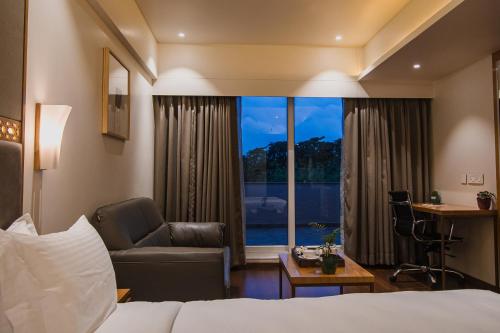 a hotel room with a bed and a chair and a window at Safal Retreat in Bhopal