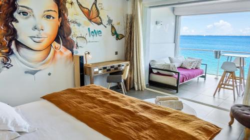 a bedroom with a bed with a painting of a woman at Residence Bleu Marine - Sea View Apartments & Studios - Saint-Martin French Side in Grand Case