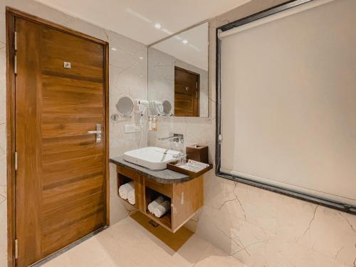 ein Badezimmer mit einem Waschbecken und einem großen Spiegel in der Unterkunft Playotel Premier Vijay Nagar in Indore