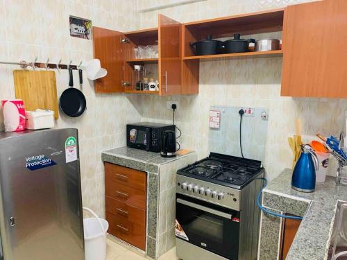 a small kitchen with a stove and a refrigerator at EM's Place Bridge View Furnished Apartments Naivasha in Naivasha