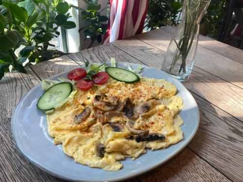 ブダペストにあるÉjjeli Bagoly Étterem és Panzióのテーブルの上にはキノコと野菜が入ったオムレツの皿がある