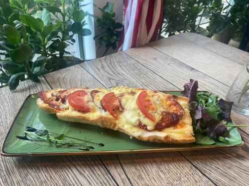 ブダペストにあるÉjjeli Bagoly Étterem és Panzióの緑の皿に載ったピザのスライスとサラダ