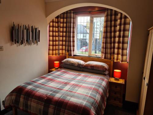 a bedroom with a bed and a window with two candles at Tudor Lodge Hotel in Nottingham