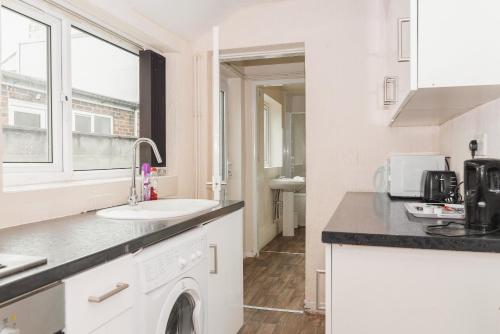 een witte keuken met een wastafel en een wasmachine bij Hanley Park House in Stoke on Trent