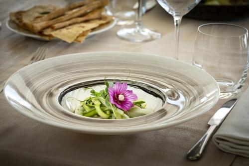 a white plate with a flower in a bowl on a table at Hotel Li Finistreddi in Cannigione