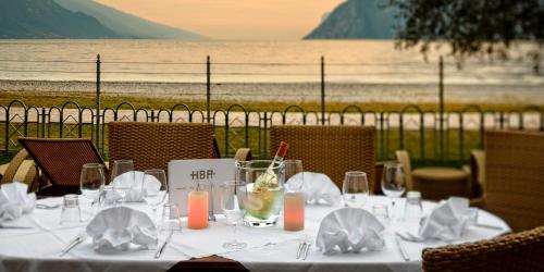 a table with white table cloths and candles and a view of the ocean at Hotel Baia Azzurra - Lake Front in Nago-Torbole