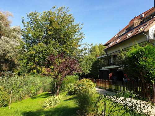 a house with a fence next to a yard at Beach Club Apartman in Mosonmagyaróvár