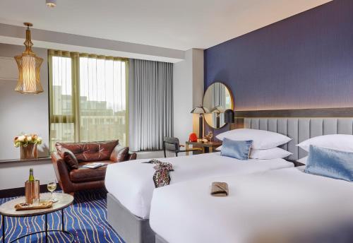 um quarto de hotel com duas camas e uma cadeira em The Grafton Hotel em Dublin