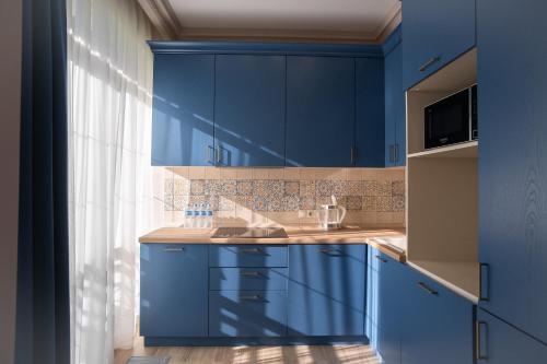 a blue kitchen with blue cabinets and a window at Art Lite One RED APARTMENTS in Adler