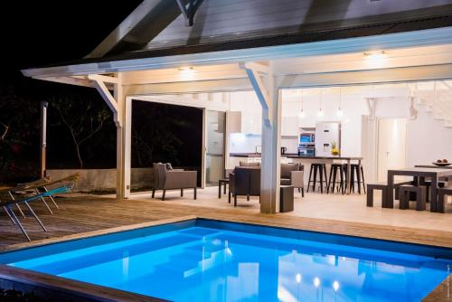 an outdoor kitchen and dining area with a pool in a house at Villa Ever Blue in Le Vauclin