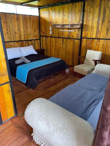 1 dormitorio con 2 camas y 1 silla en una habitación en Glamping en villa, en Villa de Leyva