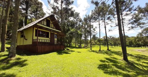 Una pequeña casa en medio de un campo con árboles. en Ranchinho da Serra chalé, en Bom Jardim da Serra
