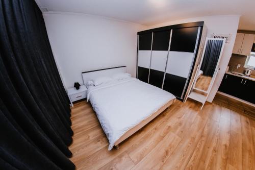 1 dormitorio con cama blanca y cortinas negras en Studio Apartment Dzungla, en Doboj