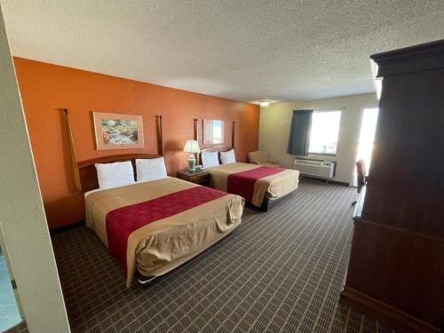 una camera d'albergo con due letti e pareti arancioni di Knights Inn & Suites Emporia a Emporia