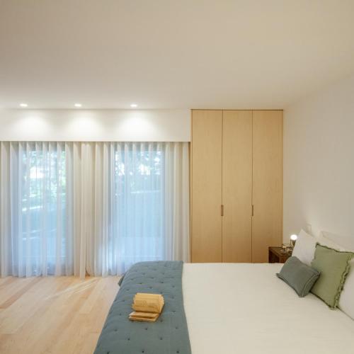 a bedroom with a large white bed and large windows at 70's wood house in Maia