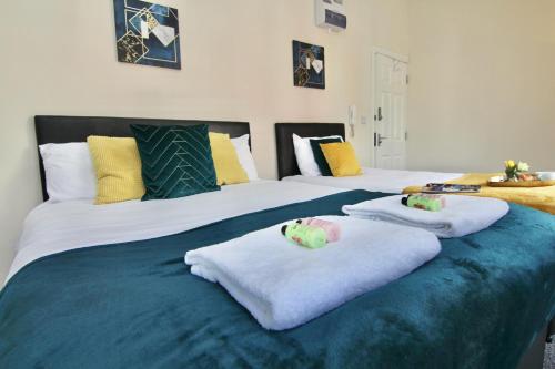 two beds with towels and stuffed animals on them at Cosy Studio 3 mins Walk To Coventry Cathedral in Coventry