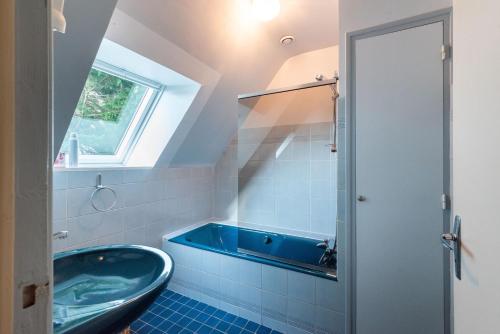 y baño con bañera azul y lavamanos. en Les Chardonnerets - Maison contemporaine Vue Mer en Clohars-Carnoët