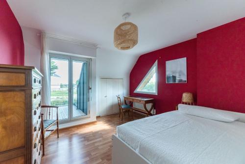 1 dormitorio con paredes rojas, 1 cama y escritorio en Les Chardonnerets - Maison contemporaine Vue Mer en Clohars-Carnoët
