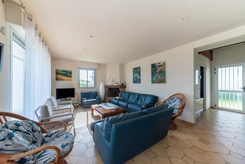 un salon avec un canapé bleu et des chaises dans l'établissement Les Chardonnerets - Maison contemporaine Vue Mer, à Clohars-Carnoët