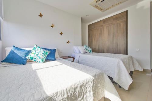 a bedroom with two beds with white and blue pillows at Beachfront Paradise with Outstanding Sunset Views in Cartagena de Indias