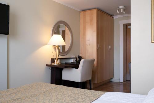 a bedroom with a desk with a lamp and a chair at Elite Stora Hotellet in Jönköping