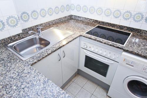 a kitchen with a sink and a washing machine at Cabo Menor 2 Planet Costa Dorada in Salou