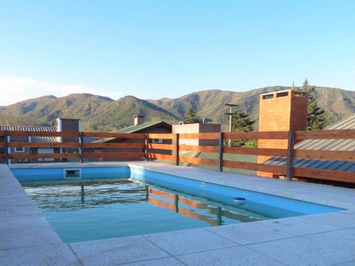 una piscina con una valla y montañas en el fondo en Cabañas Puentes Amarillos, en Santa Rosa de Calamuchita