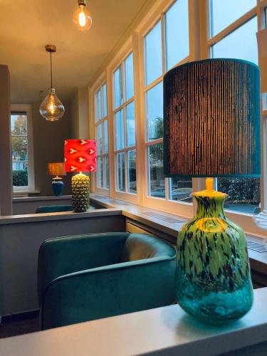 a vase sitting on a table with a lamp on a table at Meneer Pos in Velp