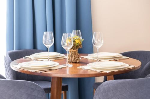 a wooden table with plates and wine glasses at Art Lite One RED APARTMENTS in Adler