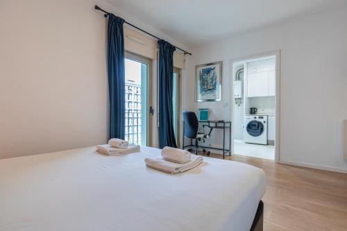 um quarto com uma cama branca com duas toalhas em Bright & Comfy Flat in Lisbon by LovelyStay em Lisboa