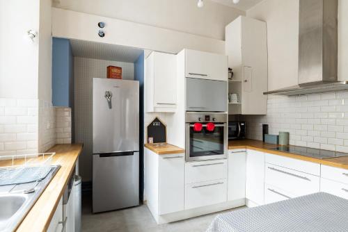 une cuisine avec des armoires blanches et un réfrigérateur en acier inoxydable dans l'établissement LE MONNAIE - Vue Cathédrale, à Rennes