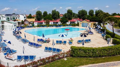 a pool with chairs and umbrellas in a resort at Camping Marelago in Caorle
