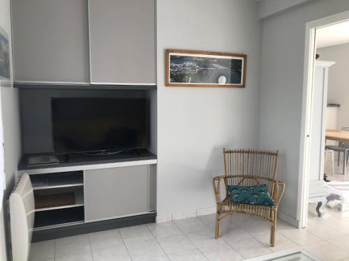ein Wohnzimmer mit einem TV und einem Stuhl in der Unterkunft La Metairina in Pénestin