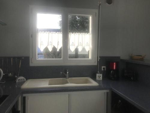 eine Küchentheke mit Spüle und zwei Fenstern in der Unterkunft La Metairina in Pénestin