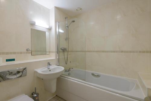 a bathroom with a sink and a toilet and a bath tub at Waves Apartments in Newquay