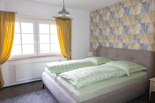 a bedroom with a bed and two windows with yellow curtains at Heidehof Jungemann in Bispingen