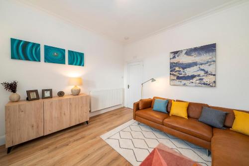 a living room with a couch and paintings on the wall at Abbotsford Apartment in Dundee
