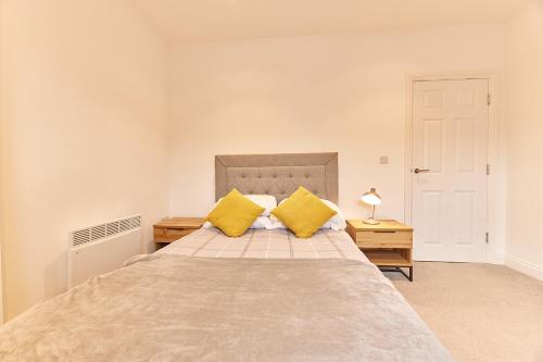 a bedroom with a large bed with two yellow pillows at Roker boutique apartment in Sunderland