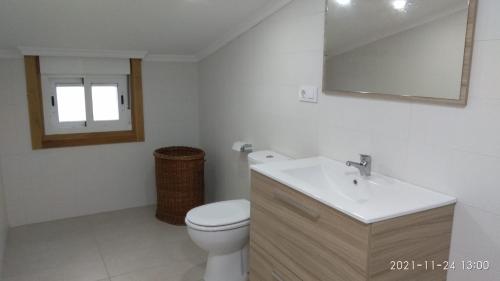 uma casa de banho com um WC, um lavatório e um espelho. em Casa compartida em Vigo