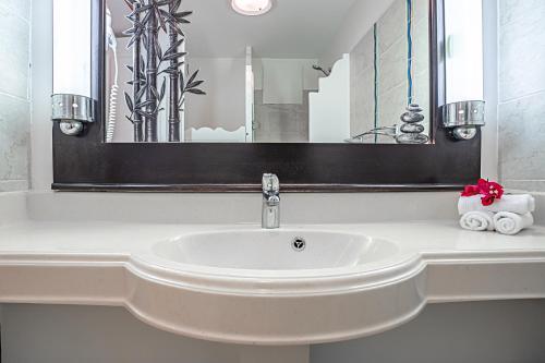 un lavandino bianco in un bagno con un grande specchio di Le Maracuja a Sainte-Anne