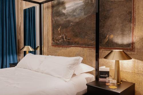 a bedroom with a white bed and a painting at Casa Conoscenti Suites in Bologna