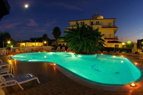 - une grande piscine en face d'un bâtiment la nuit dans l'établissement Graceland rooms and suites, à Capo Vaticano