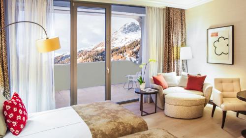 a hotel room with a bed and a couch and a window at AlpenGold Hotel Davos in Davos