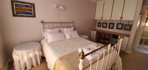 ein kleines Schlafzimmer mit einem weißen Bett und einem Tisch in der Unterkunft Hinterheim in Lambertʼs Bay