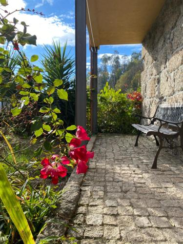 a stone walkway with a bench and red flowers at Quinta dos Mouras in Celorico de Basto