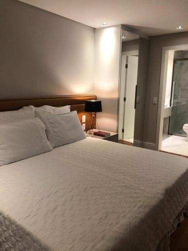 a bedroom with a large white bed and a window at Praia Brava Hotel - Apto 420 in Florianópolis