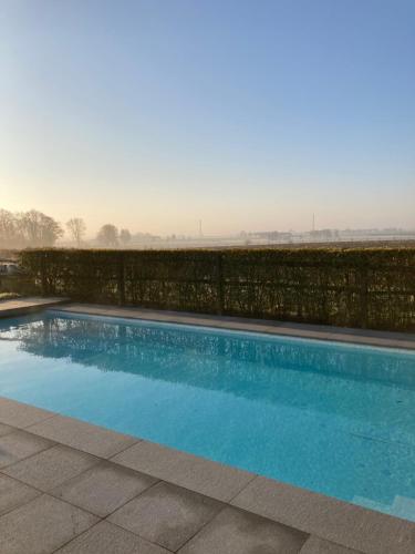 a blue swimming pool with a black fence at Maison mystique in Staden