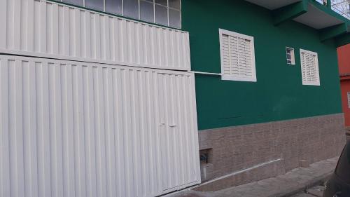 un edificio verde con puerta blanca y ventanas en Casa Magnificat, en São Thomé das Letras